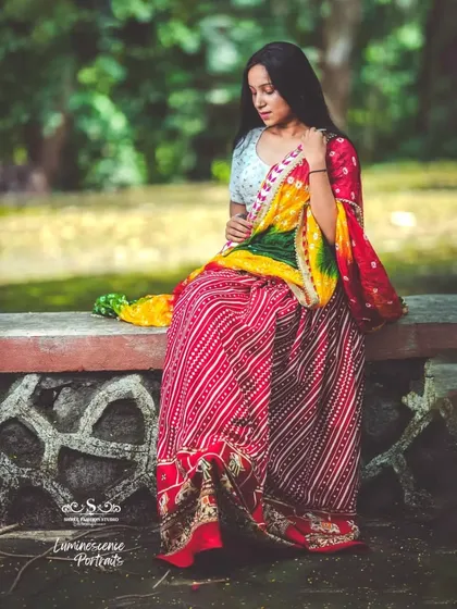 A contemplative portrait, with the model looking down, showcasing the rich textures and colors of her traditional Rajasthani-style outfit.