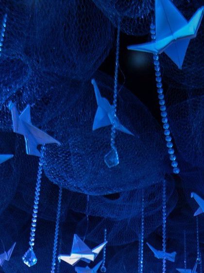 Another detailed shot of the hanging origami birds and crystals. The deep blue lighting gives the installation an ethereal, underwater-like quality.