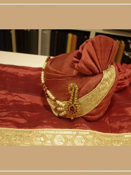 This rich maroon safa with a jeweled ornament and pearl chain is crafted to perfectly match our groom's sherwani. I ensure every element of your wedding attire is coordinated.