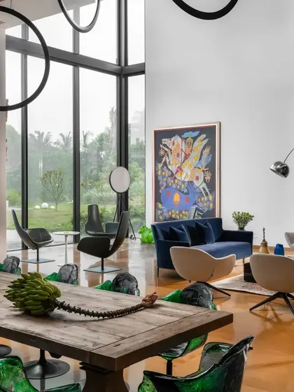 The double-height living room is a gallery for art, with large canvases and sculptural furniture set against a backdrop of floor-to-ceiling windows overlooking the garden.