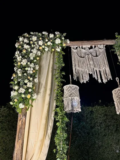 A close-up of the macrame details and the lush white floral arrangement on the bohemian wedding swing.