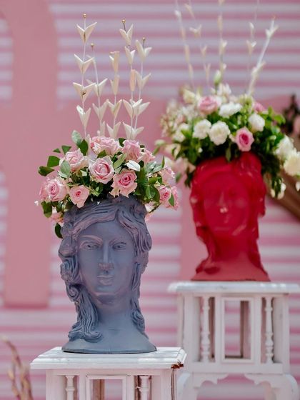 Unique floral arrangements in artistic, head-shaped vases add a touch of modern art and personality to the Mehendi decor.