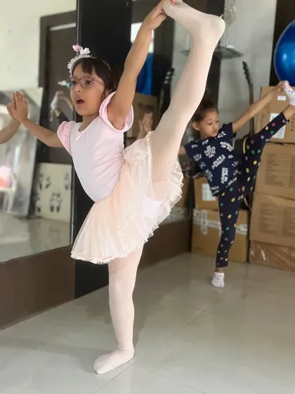 Our kids' ballet classes focus on building a strong foundation in technique, posture, and grace. This student is practicing a standing split, showcasing the flexibility and discipline we cultivate in our young dancers.