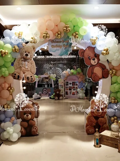A grand entrance for the rainbow and teddy bear party, featuring a large arch with multiple teddy bear cutouts and a cute van prop.