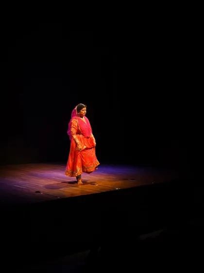 The power of a solo performer holding the stage. A single spotlight illuminates the intricate details of the costume and the focused energy of the dance, capturing the dramatic atmosphere of a classical Kathak recital.