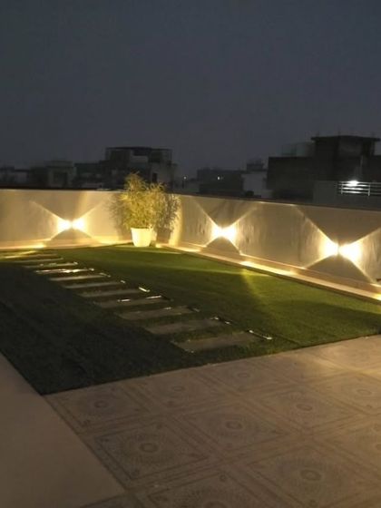 A wide view of the terrace at night, showing how a combination of pathway lights and wall lights can completely transform the space.