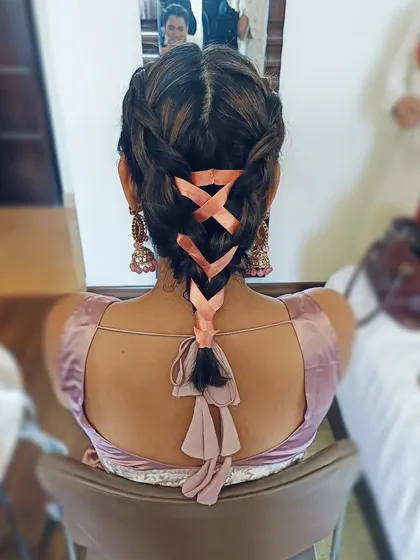 This shows my creative approach with a Dutch braid intricately woven with a soft peach ribbon. This is a great way to incorporate your outfit's color into the hairstyle, perfect for a Mehendi or Haldi ceremony.