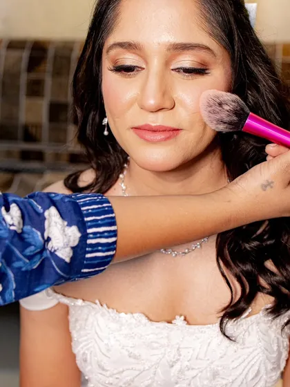 A behind-the-scenes look at my process. Here, I'm applying a soft blush to add a natural, healthy flush to the bride's cheeks, enhancing her beautiful smile.