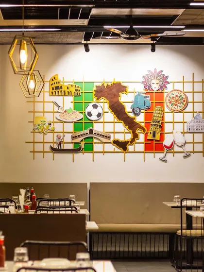 A detailed look at the custom-designed wall art that serves as a focal point. This piece is an ensemble of classic Italian motifs, from the map of Italy to a Vespa and the Colosseum, all mounted on a golden grid.