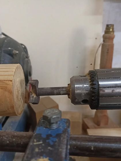 Using a Forstner bit in the tailstock of the lathe to drill out the inside of the box. This ensures a clean, flat-bottomed hole.