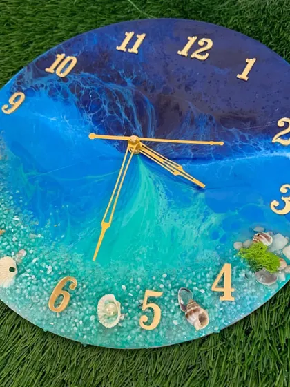 This ocean clock uses Arabic numerals and features a vibrant shoreline with shells and mossy green accents.