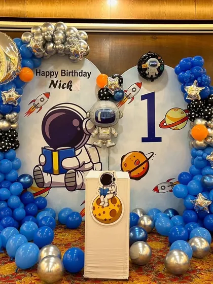We created an out-of-this-world astronaut theme for Nick's first birthday. The decor includes a custom space backdrop, balloon columns in blue, silver, and black, and special foil balloons like a crescent moon and an astronaut.