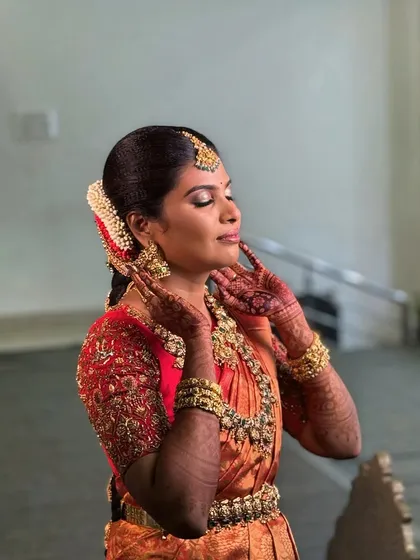 A creative pose from Abi, showcasing her gorgeous makeup and henna-adorned hands. The golden tones in her eyeshadow perfectly match her traditional gold jewellery.