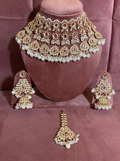 A flat lay of the red and pearl kundan set, showing all the pieces together.