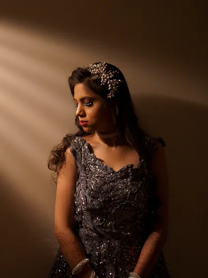 An artistic portrait of the bride in her glamorous reception gown. I use dramatic lighting to create a sophisticated and moody shot that highlights her elegance.