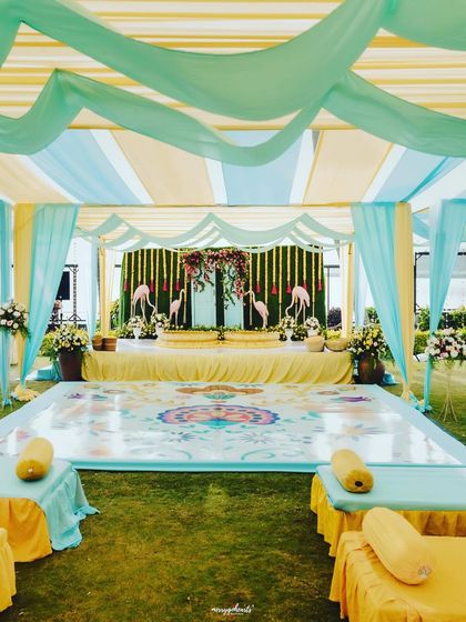 A wide shot of the pastel-themed Haldi setup, with a custom-printed dance floor and elegant draping creating a soft and dreamy look.
