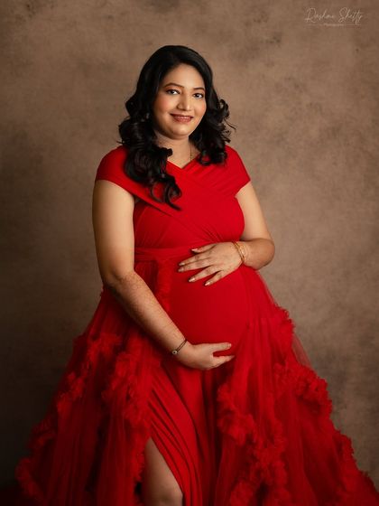 A classic and joyful maternity portrait. The mom-to-be’s warm smile and the way she cradles her bump in this elegant red gown make for a truly heartwarming image.