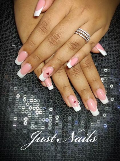 A classic French manicure on square-shaped nails with a tiny, hand-painted red heart accent.