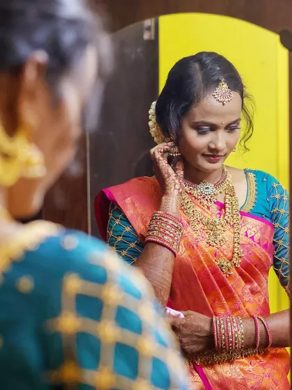 A quiet moment as the bride gets ready. I captured this over-the-shoulder shot to show her final touches in the mirror, highlighting the intricate details of her temple jewellery and the beautiful silk saree.