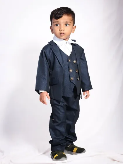 A classic full-body portrait of a toddler in a three-piece suit. The simple white background keeps the focus entirely on him and his very grown-up outfit.