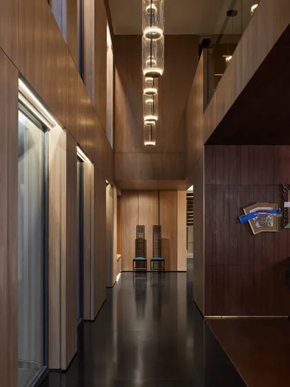 The passage leading to the dining room at Baid Residence. It features modern lighting from Flos, statement chairs by Pallucco, and sleek black granite flooring for a timelessly sophisticated look.