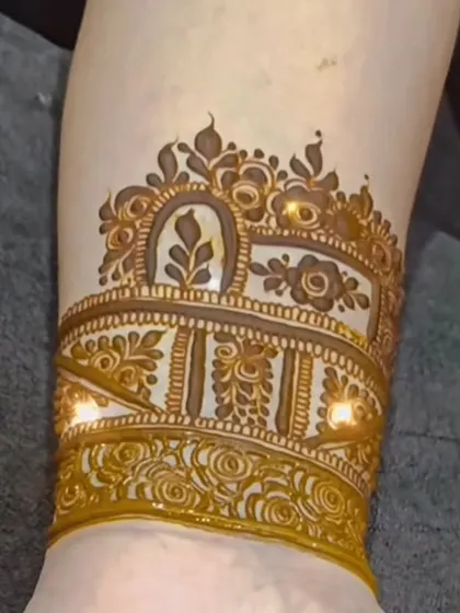 A detailed shot of the arm band, featuring delicate arches and floral motifs. It looks like a piece of jewelry.