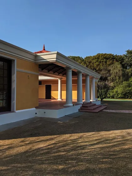 An upcoming farmhouse project on the outskirts of Delhi, featuring a colonnaded verandah. The design fuses modern architectural lines with traditional Indian materials to evoke a timeless, lived-in charm.