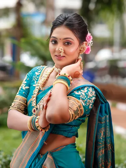 This pose highlights the elegant hairstyle and the floral accessories, which are key elements of the Maharashtrian bridal look.