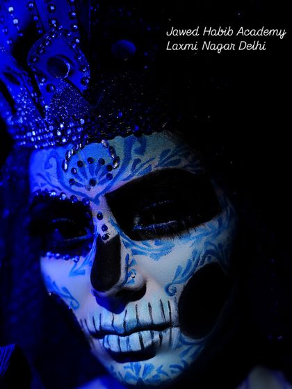 A close-up of a beautifully detailed sugar skull makeup look, illuminated by blue light. We teach the fine art of line work and shading for intricate fantasy designs.