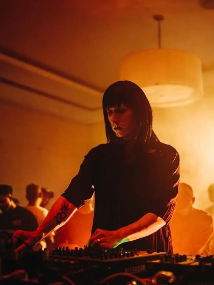 A guest artist is bathed in warm, ethereal light, creating a dream-like atmosphere during her set. The visual production is as important as the sound.