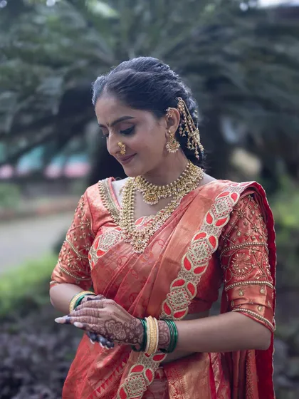 A beautiful candid shot showing the intricate details of the red Nauvari saree and the traditional gold jewelry.