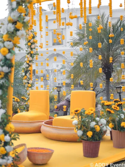 A close-up of the Haldi seating area, showing the intricate floral garlands and comfortable chairs for the couple.