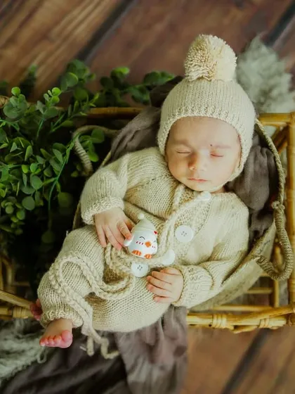 An overhead view of this sleeping angel. The textures of the basket, greenery, and his outfit create a rich and beautiful newborn portrait.