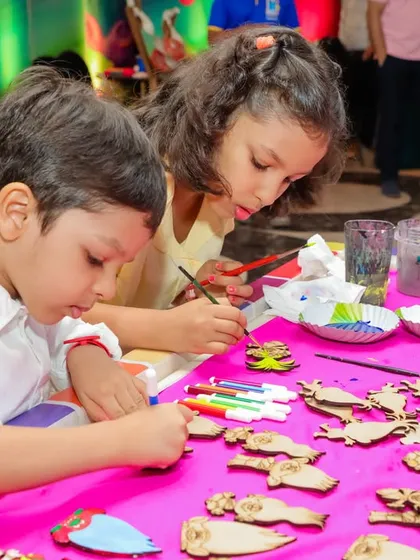 The magnet painting activity station at the Trolls-themed party. The bright pink tablecloth and colorful supplies add to the festive atmosphere.