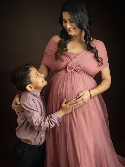 The joy on your older son's face is just priceless. Including siblings in the maternity shoot is a wonderful way to capture the whole family's excitement.