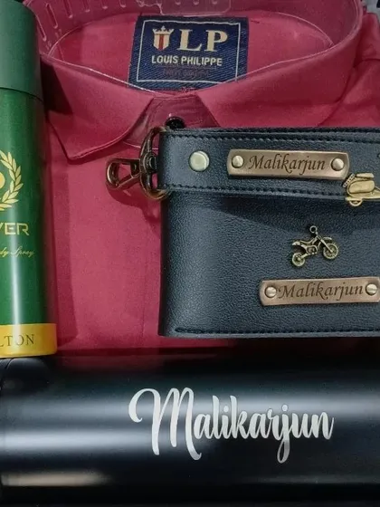 This gift hamper pairs a red shirt with a personalized black leather wallet and keychain, a name-engraved bottle, and deodorant.