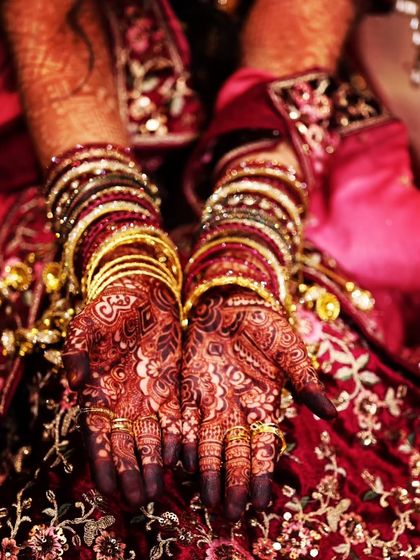 A beautiful top-down shot of the bride's hands, showcasing the rich, dark stain of her bridal mehendi.