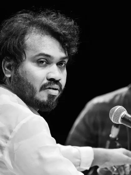 A close-up portrait in black and white, capturing a moment of quiet contemplation during a concert.