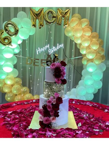 The 60th birthday spacer cake in its full glory, surrounded by a beautiful balloon arch and rose petals.
