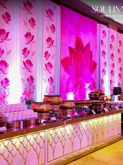 A grand buffet station set against a backdrop of pink lotus-themed decor, reflecting a blend of tradition and modern elegance. Our thematic setups are designed to perfectly match the vision of your wedding.