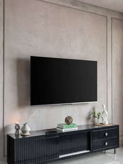 The TV unit in 'Maison-De-Confort'. The textured lime-wash wall and minimalist black console create a sophisticated, modern look.
