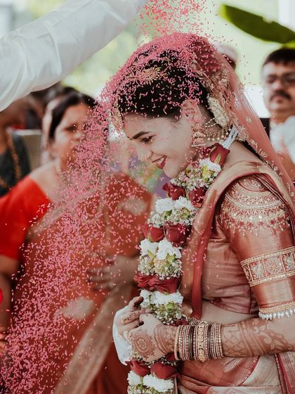Another perspective of the petal shower, showing the beautiful cascade of pink over the bride in her traditional red and gold saree.