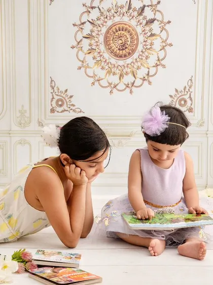 A big sister reads a story to her younger sibling, a quiet and beautiful moment of connection and shared imagination.