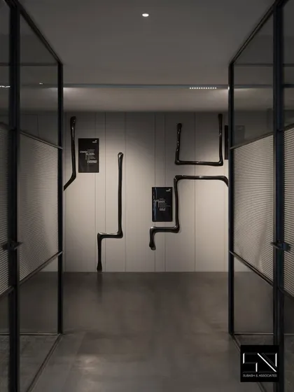 An art-filled corridor with dramatic black sculptural pieces mounted on the wall. This transforms a simple passageway into a gallery-like experience, reflecting the company's creative and modern identity.