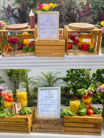This is a great example of our rustic and vibrant setup for an outdoor brunch. We use wooden crates, fresh flowers, and colorful vegetables to create an inviting and photogenic live pizza and pasta station that enhances the party's decor.