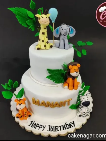 A clean and modern two-tiered jungle cake with adorable fondant animals. The simple white background makes the colorful characters pop.