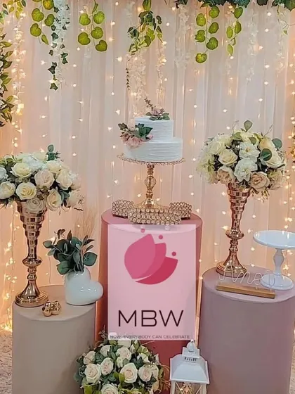 A romantic and elegant cake table setup. This design uses soft pink pedestals, beautiful white and blush floral arrangements, and cascading fairy lights for a dreamy effect.