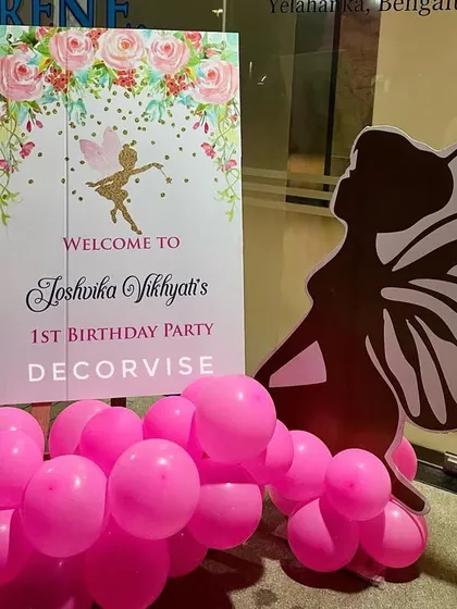 A close-up of the personalized welcome sign for Joshvika's first birthday. The sign features a floral fairy design and is paired with a silhouette cutout, setting the enchanting tone for the event.