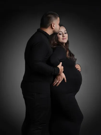 A powerful and intimate black and white portrait. The dramatic lighting creates a beautiful silhouette, emphasizing the baby bump.