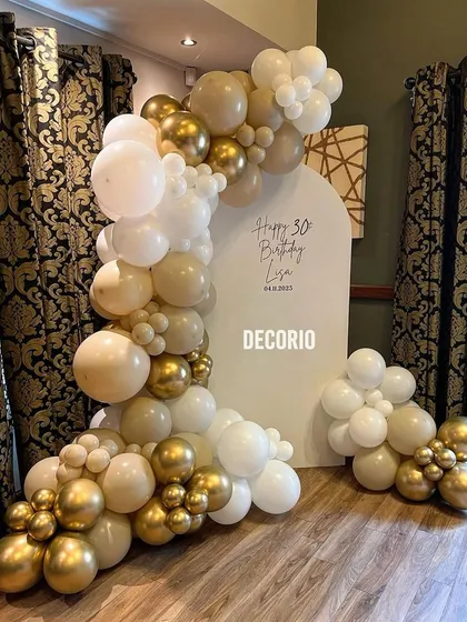 A clean and elegant 30th birthday decoration with a neutral color palette. This setup uses a simple arched backdrop personalized for 'Lisa', framed by a tasteful arrangement of white, nude, and gold balloons.